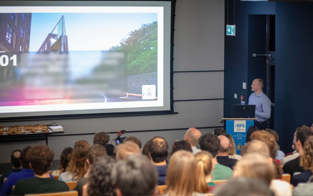 Img: Stephen Gilmore presenting to the Crux team i an auditorium