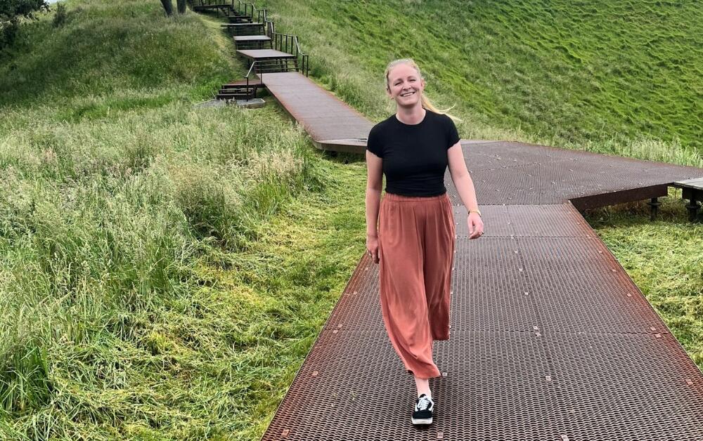 Image: Elllie Lewis, Senior Project Manager, crux, walking down a path in New Zealand with grass either side