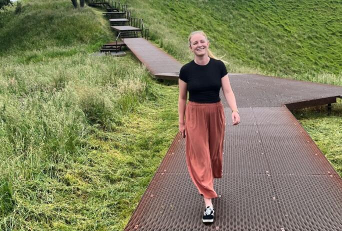 Image: Elllie Lewis, Senior Project Manager, crux, walking down a path in New Zealand with grass either side