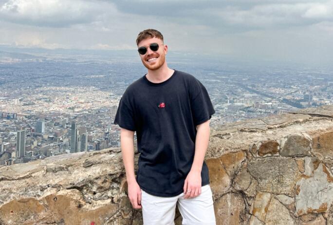 Image: George Watts of Crux in Columbia, with a wall behind him and the Columbian city of Bogota behind him