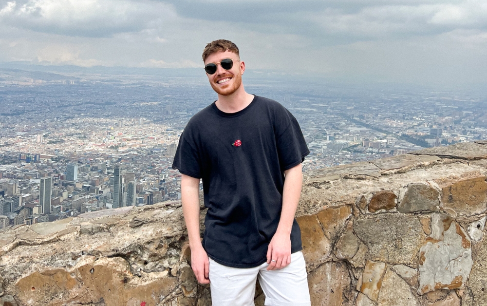 Image: George Watts of Crux in Columbia, with a wall behind him and the Columbian city of Bogota behind him